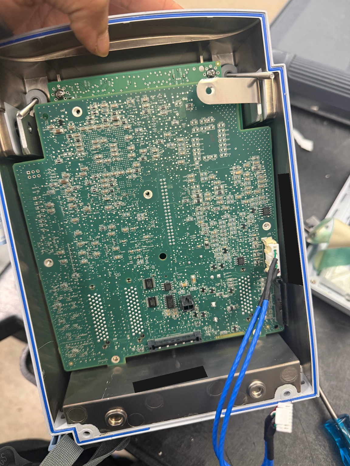 Opened Alaris 8015 housing with the internal circuit board exposed and equipment identifiers masked.