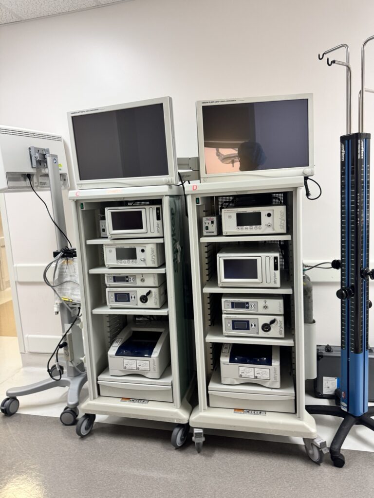 Two surgical equipment towers with monitors and stacked medical devices