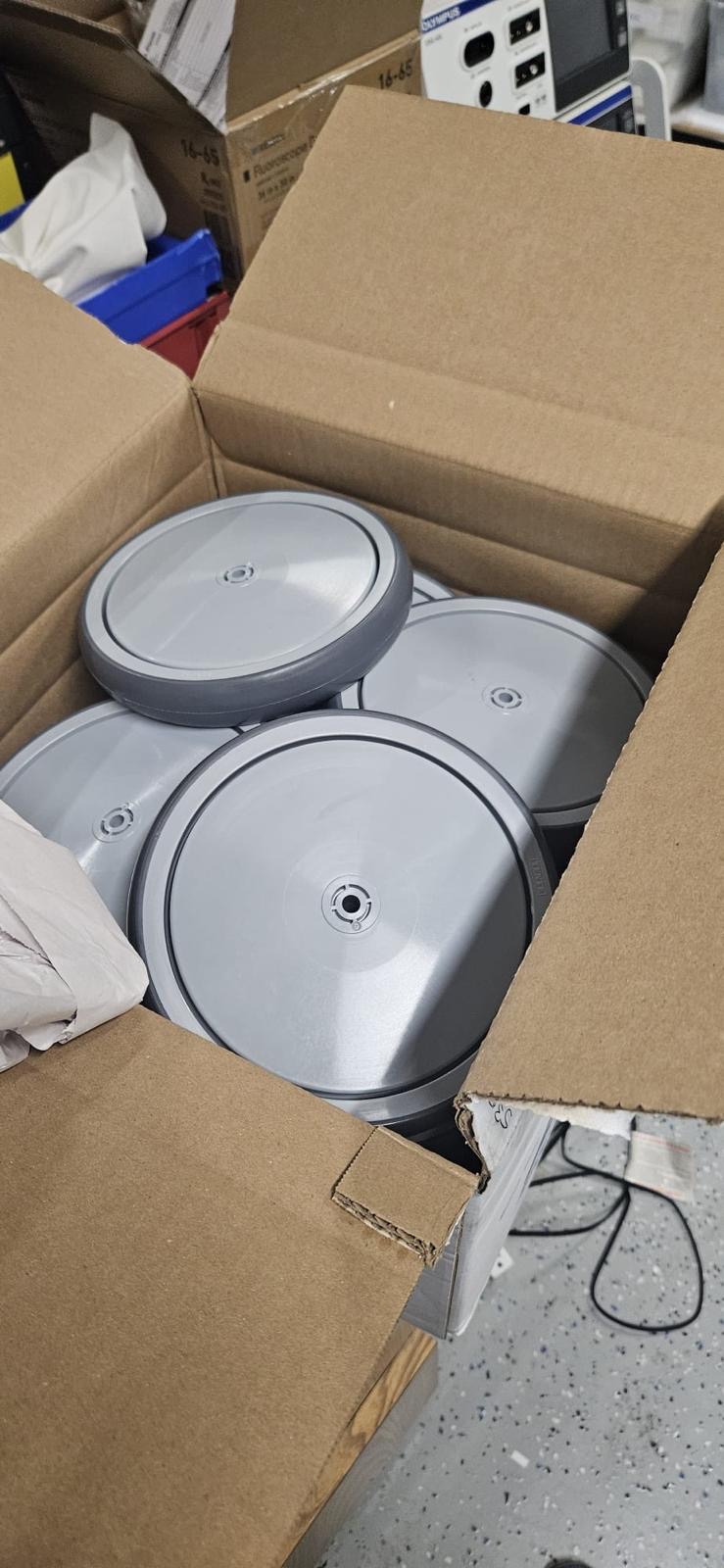 Patient-bed wheel assemblies arranged in a box during mechanical service.