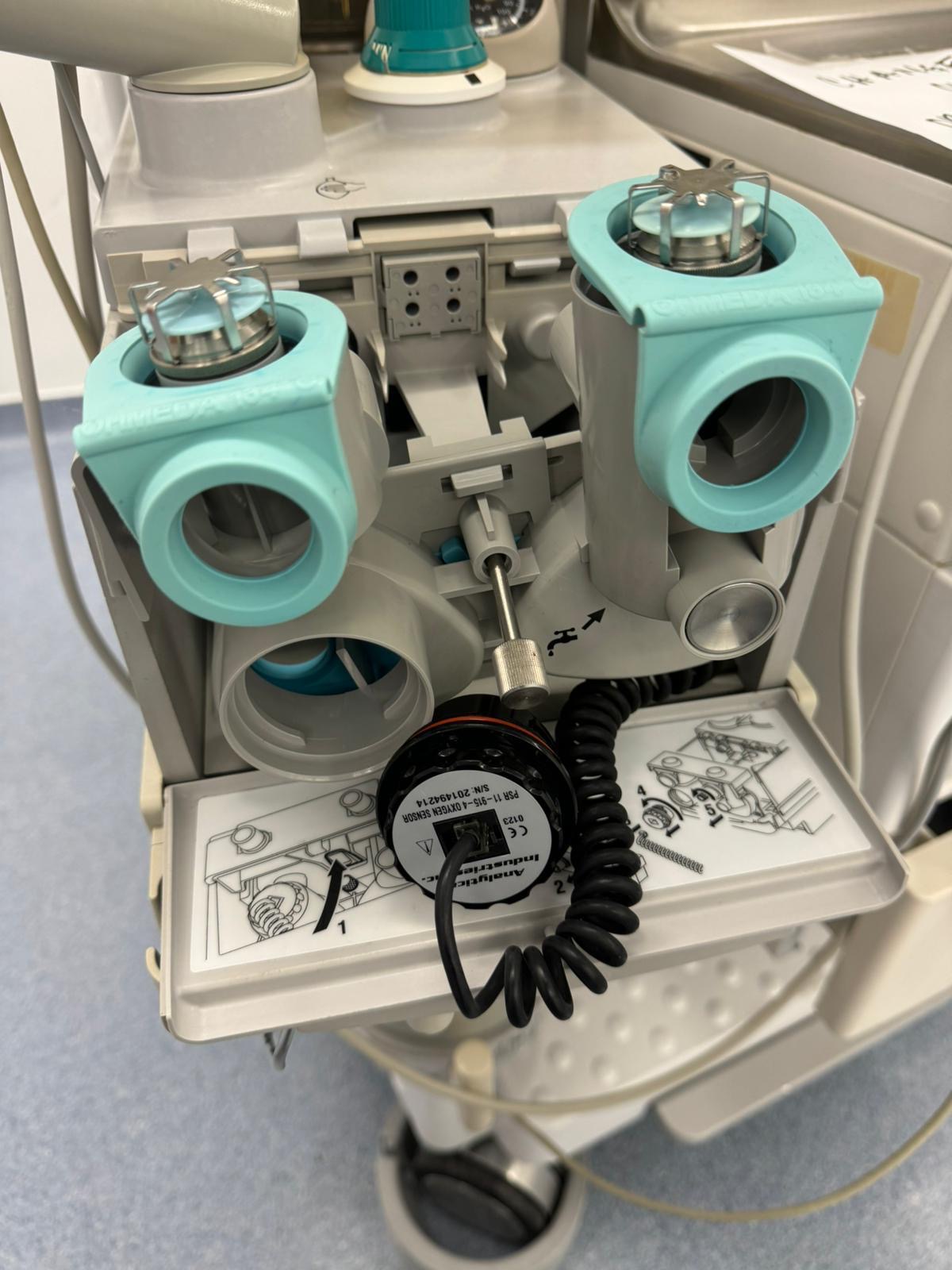 Open breathing-system compartment of a GE anesthesia machine during preventive maintenance, with connected oxygen sensor visible.
