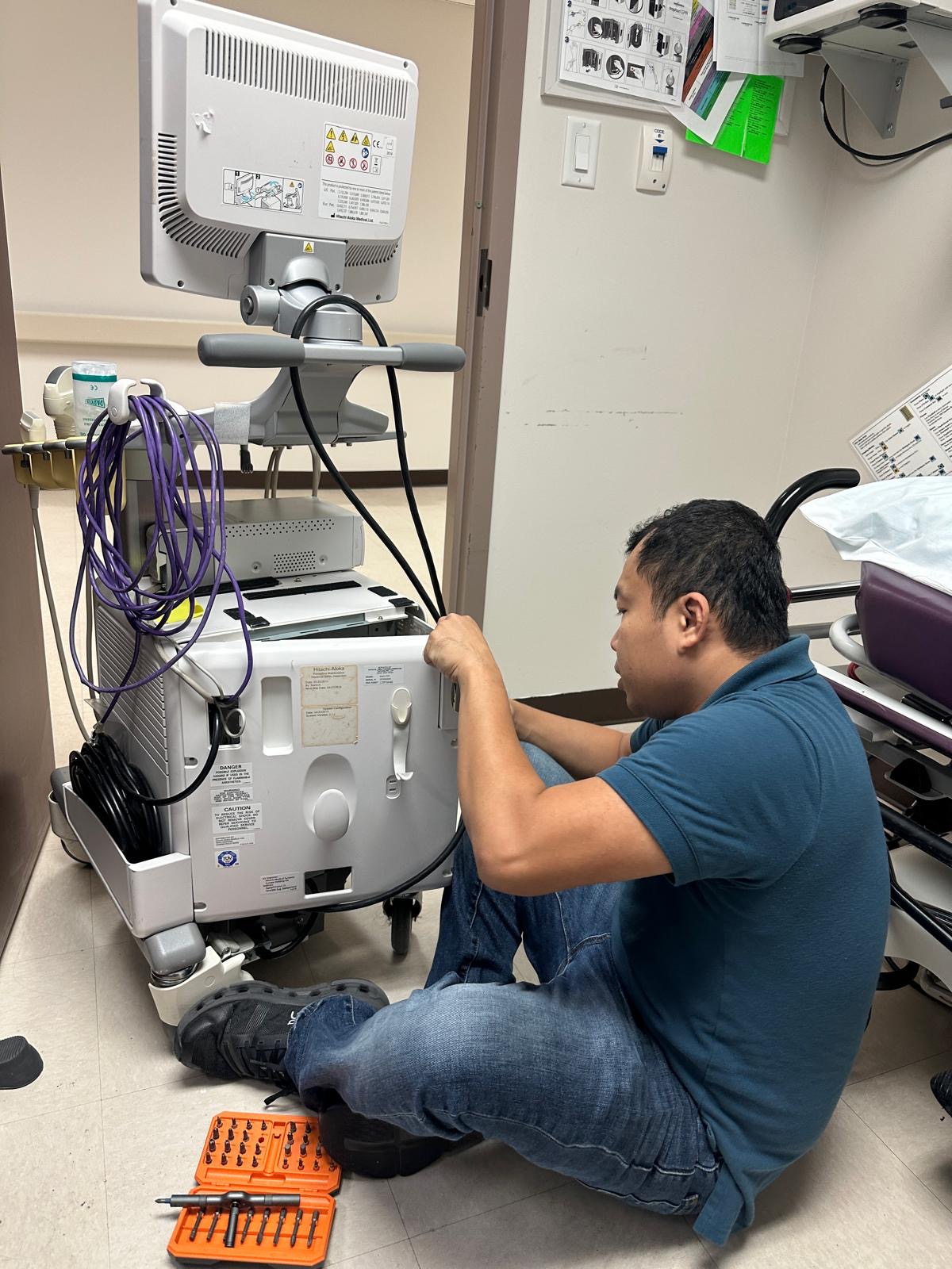 Technician accessing a Hitachi Aloka ProSound F37 ultrasound system for preventive maintenance