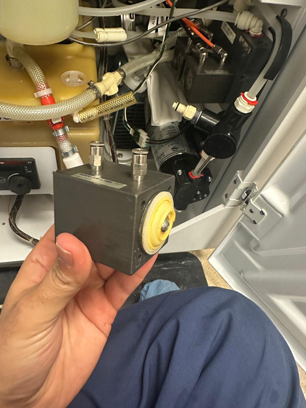 Medivators air valve held in front of the open endoscope reprocessor service compartment.