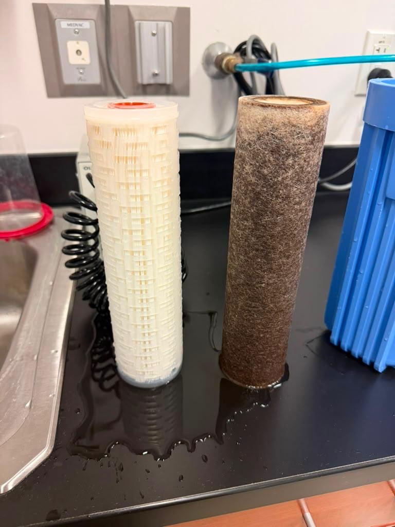 Replacement and used Medivators water filter cartridges side by side beside a blue filter housing.