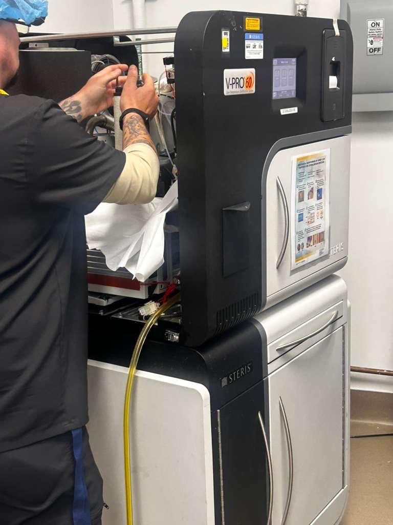STERIS V-PRO 60 sterilizer with its side service panel open during vacuum pump oil maintenance.